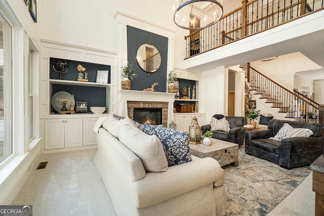 3227 Aviary Ct NW, Acworth, GA 30101 - carpeted living area featuring a high ceiling, built in shelves, stairs, a stone fireplace, and a chandelier