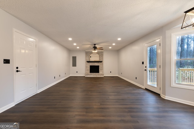 unfurnished living room featuring dark wood finished floors, ceiling fan, a wealth of natural light, and a fireplace