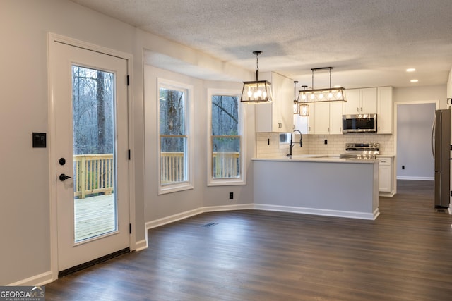 kitchen featuring a textured ceiling, decorative backsplash, white cabinetry, light countertops, and appliances with stainless steel finishes