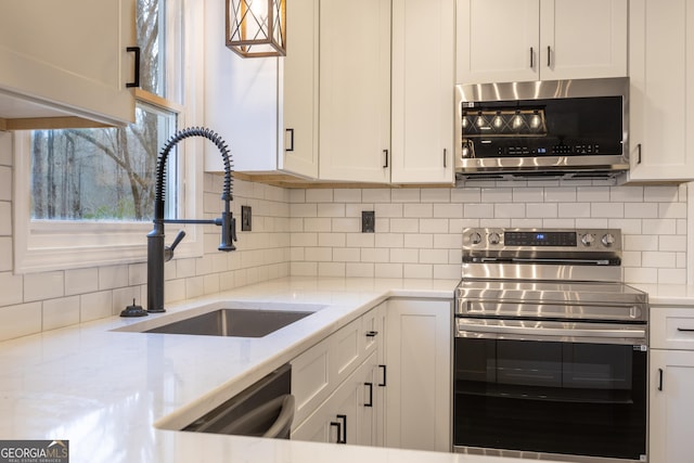 kitchen with white cabinets, stainless steel appliances, a sink, and backsplash