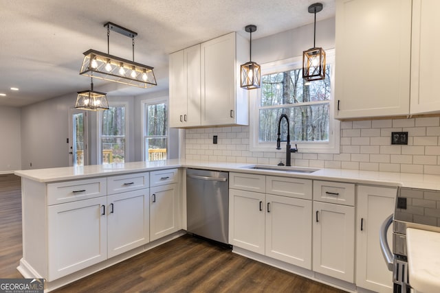 kitchen featuring light countertops, stainless steel dishwasher, a sink, a peninsula, and dark wood-style flooring