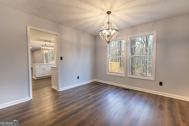 spare room featuring baseboards, dark wood-style flooring, and an inviting chandelier