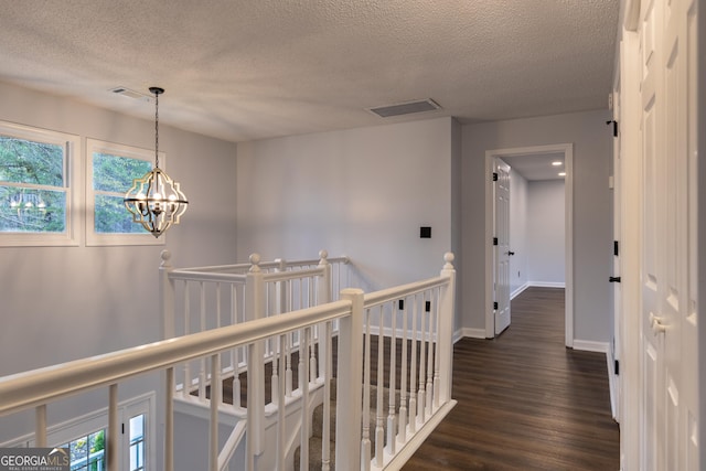 corridor featuring a wealth of natural light, dark wood-type flooring, an upstairs landing, and a textured ceiling