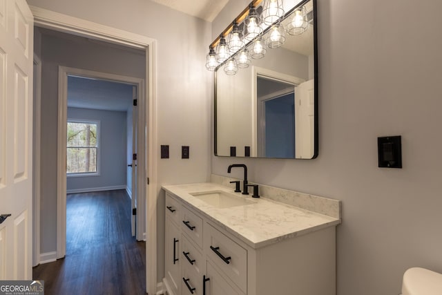bathroom featuring baseboards, wood finished floors, vanity, and toilet