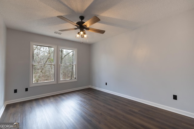 empty room featuring ceiling fan, visible vents, baseboards, and dark wood-style flooring