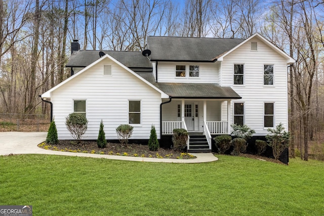 traditional-style home featuring a chimney, a front yard, a shingled roof, and covered porch