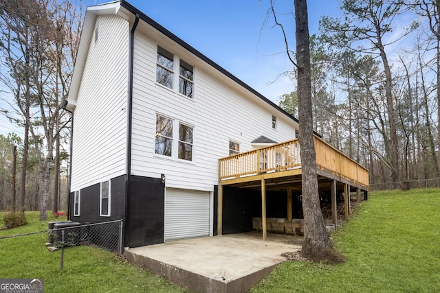 back of property with fence, a wooden deck, a yard, and a garage