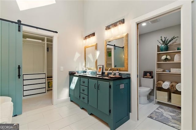 bathroom featuring a spacious closet, vanity, and toilet