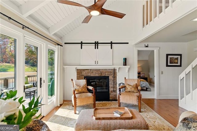 living area featuring high vaulted ceiling, beamed ceiling, light wood-style flooring, a ceiling fan, and baseboards