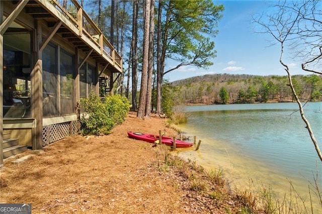 view of yard with a water view, a view of trees, and a sunroom