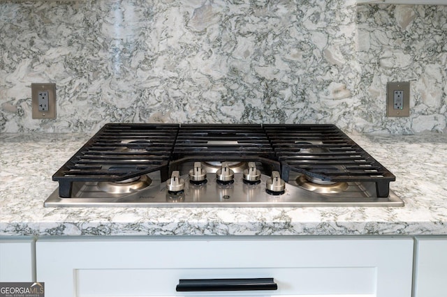 details featuring stainless steel gas stovetop and tasteful backsplash