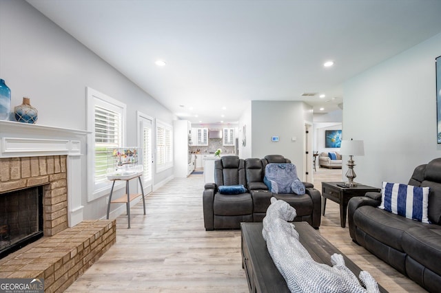living room with recessed lighting, baseboards, a fireplace, and light wood-type flooring