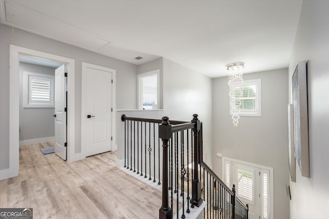 hall featuring attic access, baseboards, an upstairs landing, and light wood-style flooring