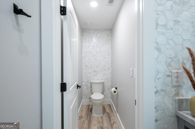 bathroom with baseboards, visible vents, wood finished floors, and toilet