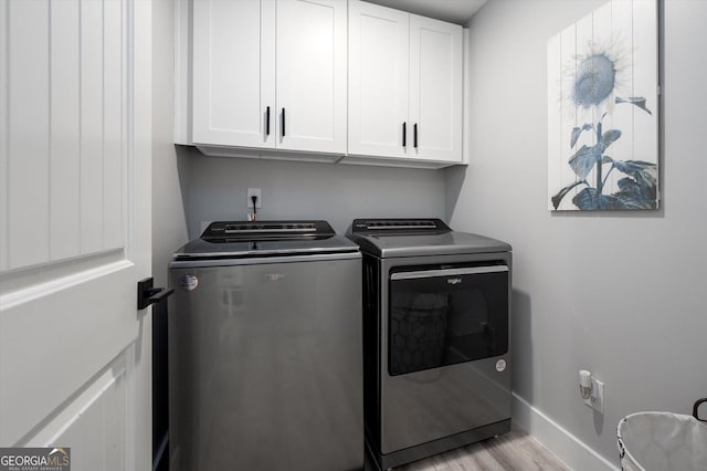 washroom featuring washing machine and clothes dryer, cabinet space, light wood-style flooring, and baseboards