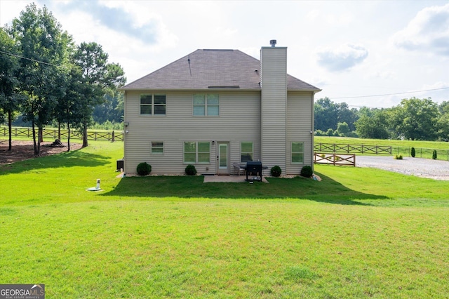 back of property with a chimney, fence, a yard, and a patio area