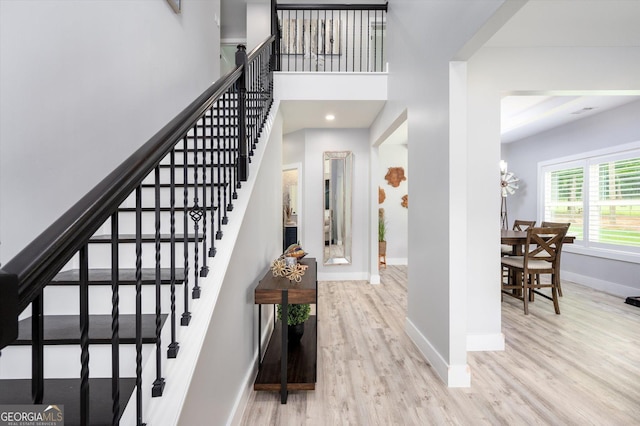 foyer entrance featuring baseboards, a towering ceiling, wood finished floors, recessed lighting, and stairway