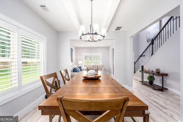 dining space featuring baseboards, visible vents, a chandelier, and light wood-style floors