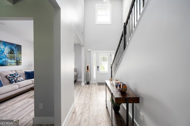 entrance foyer featuring stairs, wood finished floors, a towering ceiling, and baseboards