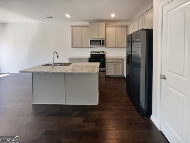 7109 Gladstone Cir, Lithonia, GA 30038 - kitchen featuring appliances with stainless steel finishes, light stone counters, decorative backsplash, a center island with sink, and dark wood-type flooring