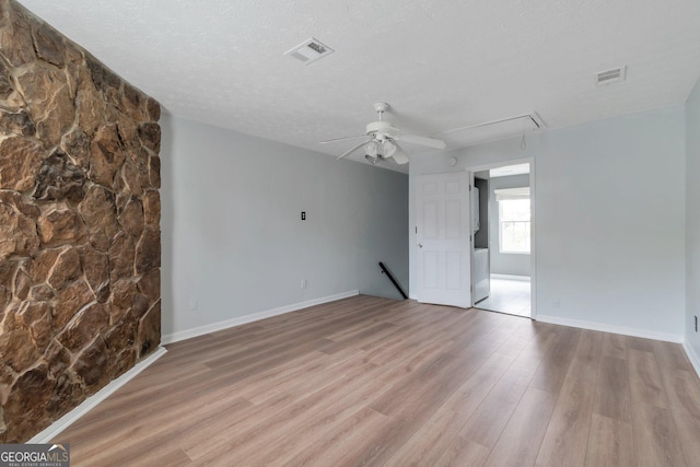 spare room featuring attic access, visible vents, wood finished floors, and a ceiling fan