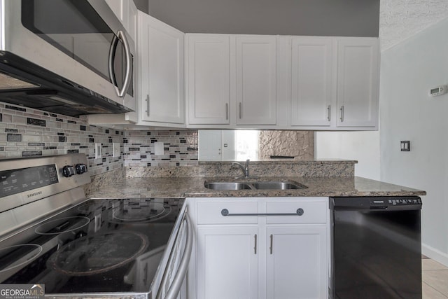 kitchen with stainless steel appliances, decorative backsplash, a sink, stone countertops, and white cabinets