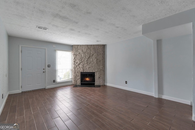 unfurnished living room featuring baseboards, visible vents, a fireplace, and dark wood-style flooring