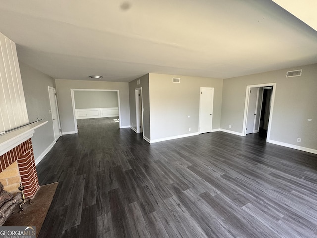 unfurnished living room with dark wood-style floors, baseboards, a fireplace, and visible vents