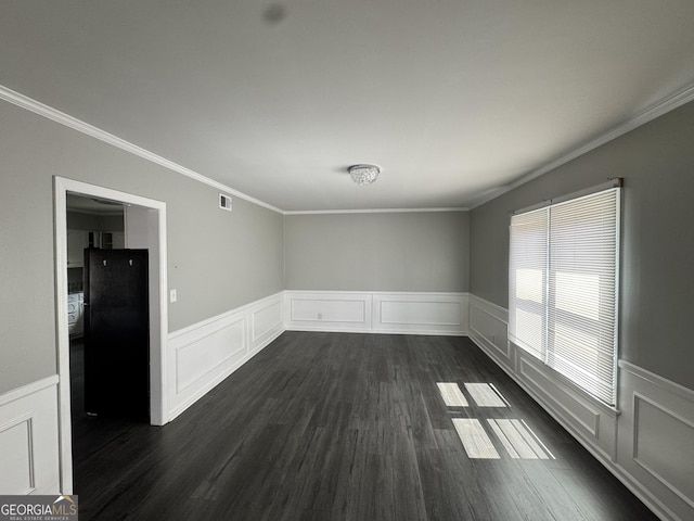 unfurnished room featuring a wainscoted wall, visible vents, crown molding, and dark wood-style flooring