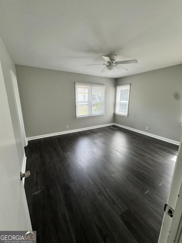 spare room with dark wood finished floors, baseboards, and a ceiling fan