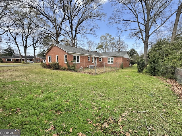 exterior space featuring a lawn, fence, and brick siding
