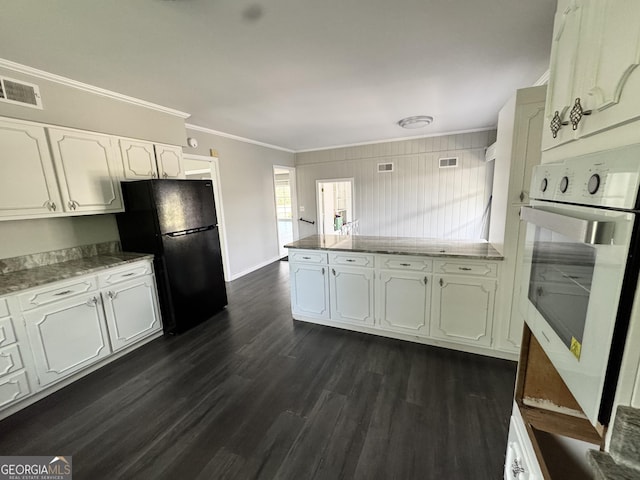 kitchen featuring oven, dark wood-style flooring, freestanding refrigerator, white cabinets, and a peninsula
