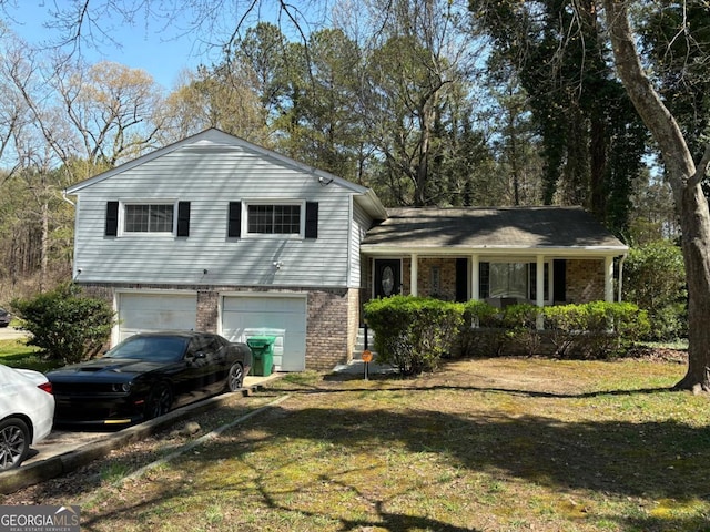 tri-level home featuring brick siding, a front yard, driveway, and an attached garage