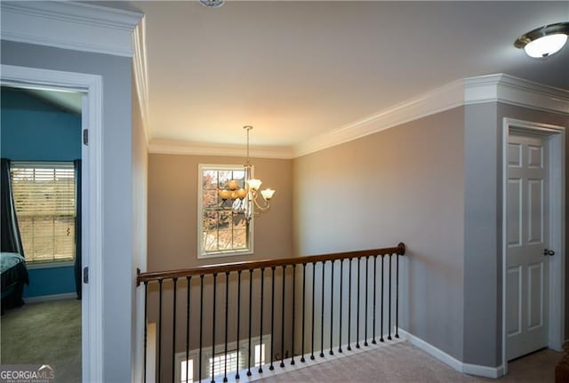 hall featuring a chandelier, baseboards, ornamental molding, and carpet floors