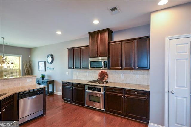 kitchen with dark wood-type flooring, dark brown cabinetry, light stone counters, and appliances with stainless steel finishes