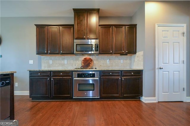 kitchen featuring dark wood-type flooring, tasteful backsplash, appliances with stainless steel finishes, and baseboards