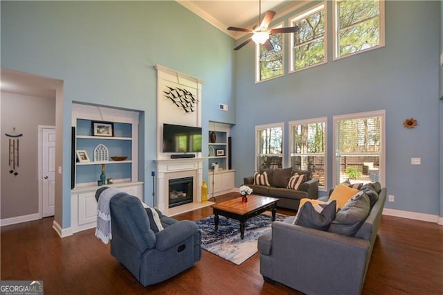 living room with a high ceiling, ceiling fan, dark wood finished floors, and plenty of natural light