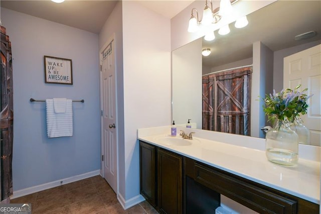 bathroom featuring tile patterned flooring, baseboards, an inviting chandelier, and vanity