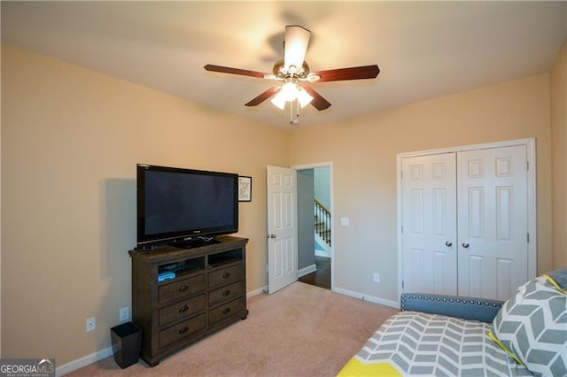 bedroom with a closet, light colored carpet, baseboards, and a ceiling fan