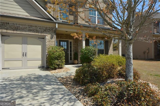 view of exterior entry with brick siding and driveway