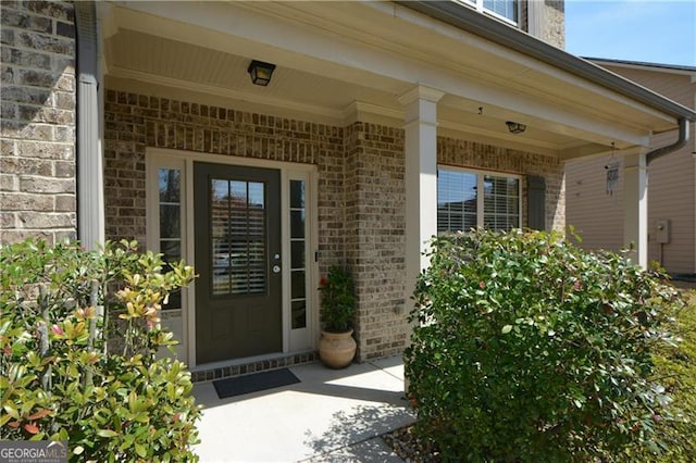 doorway to property with covered porch and brick siding