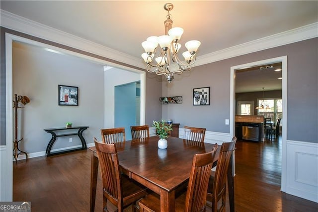 dining area featuring dark wood-type flooring, a notable chandelier, and ornamental molding