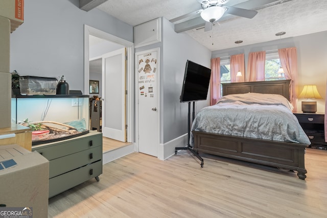 bedroom featuring light wood finished floors, a ceiling fan, beamed ceiling, baseboards, and a textured ceiling