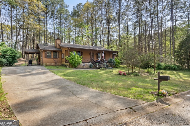 view of front of house with a chimney, a front lawn, driveway, covered porch, and an attached carport