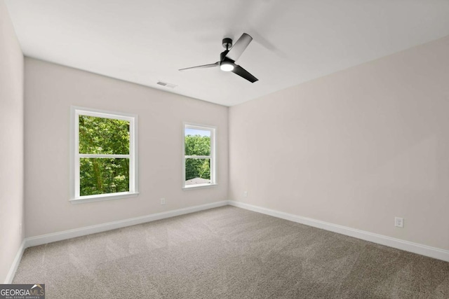 carpeted empty room with baseboards, visible vents, and ceiling fan