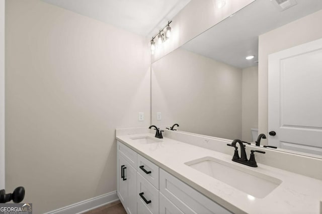 bathroom with toilet, a sink, baseboards, and visible vents