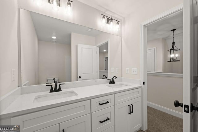 bathroom with double vanity, baseboards, a sink, and an inviting chandelier