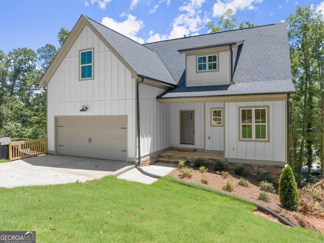 modern inspired farmhouse featuring a front lawn, a shingled roof, a garage, and concrete driveway