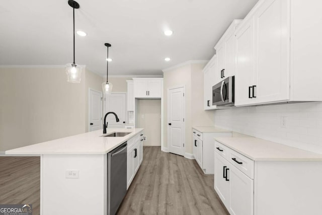 kitchen with crown molding, a sink, light wood finished floors, tasteful backsplash, and stainless steel appliances