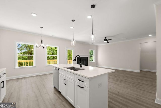 kitchen with light countertops, a sink, dishwasher, light wood-type flooring, and a healthy amount of sunlight